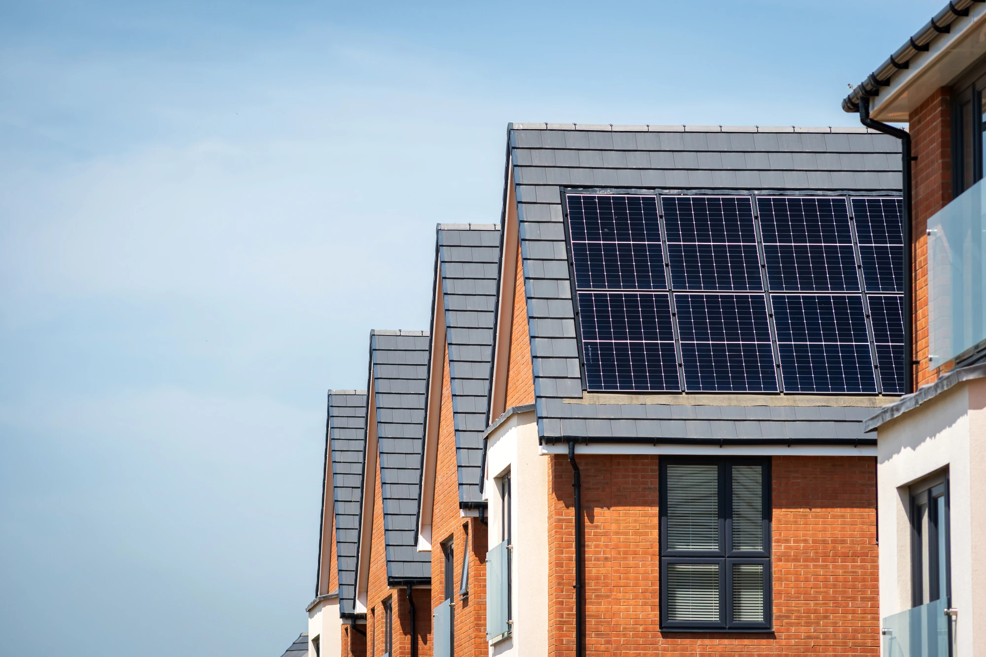 Row of modern homes with black solar PV panels installed on their roofs, showing residential solar panels in Ireland